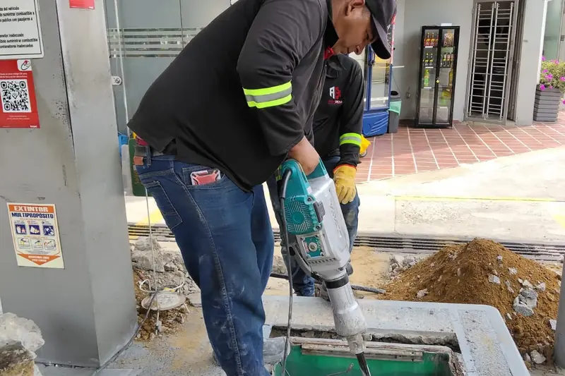 Técnico demoliendo concreto con martillo eléctrico para intervenir una caja contenedora